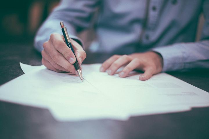 Business owner writing and reviewing financial paperwork with a pen