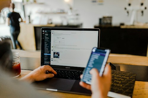 Business owner reviewing revenue on a laptop and phone