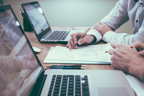 Business owner signing SBA loan paperwork next to a laptop